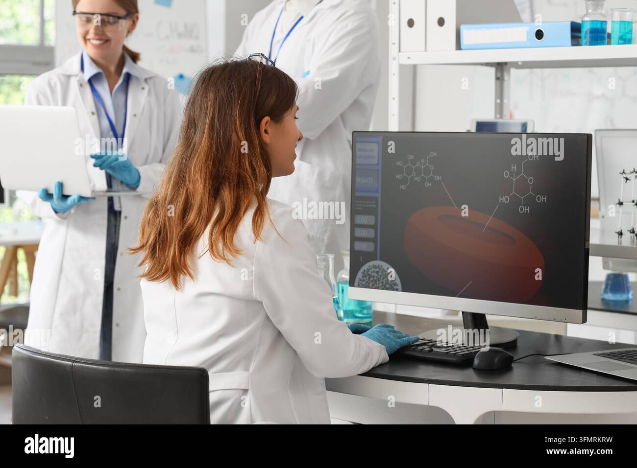 Medical research and pharmaceutical development, scientists analyzing molecular structures on computer in laboratory with team collaboration and data Stock Photo