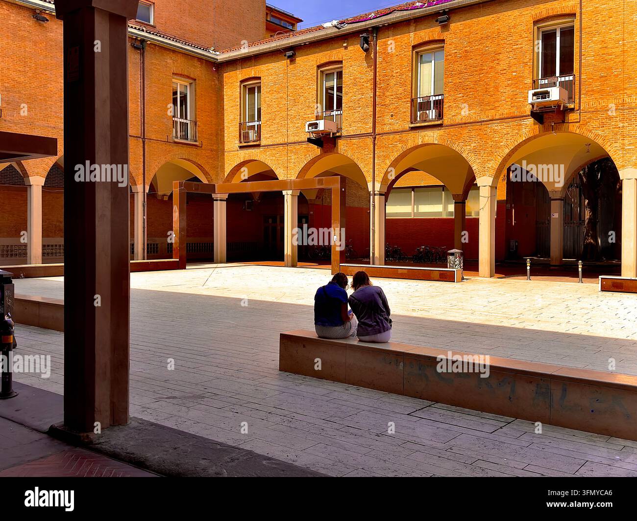 Historic University of Bologna in Bologna, Italy, with two university students in the foreground. - Smartphone Captured Stock Image