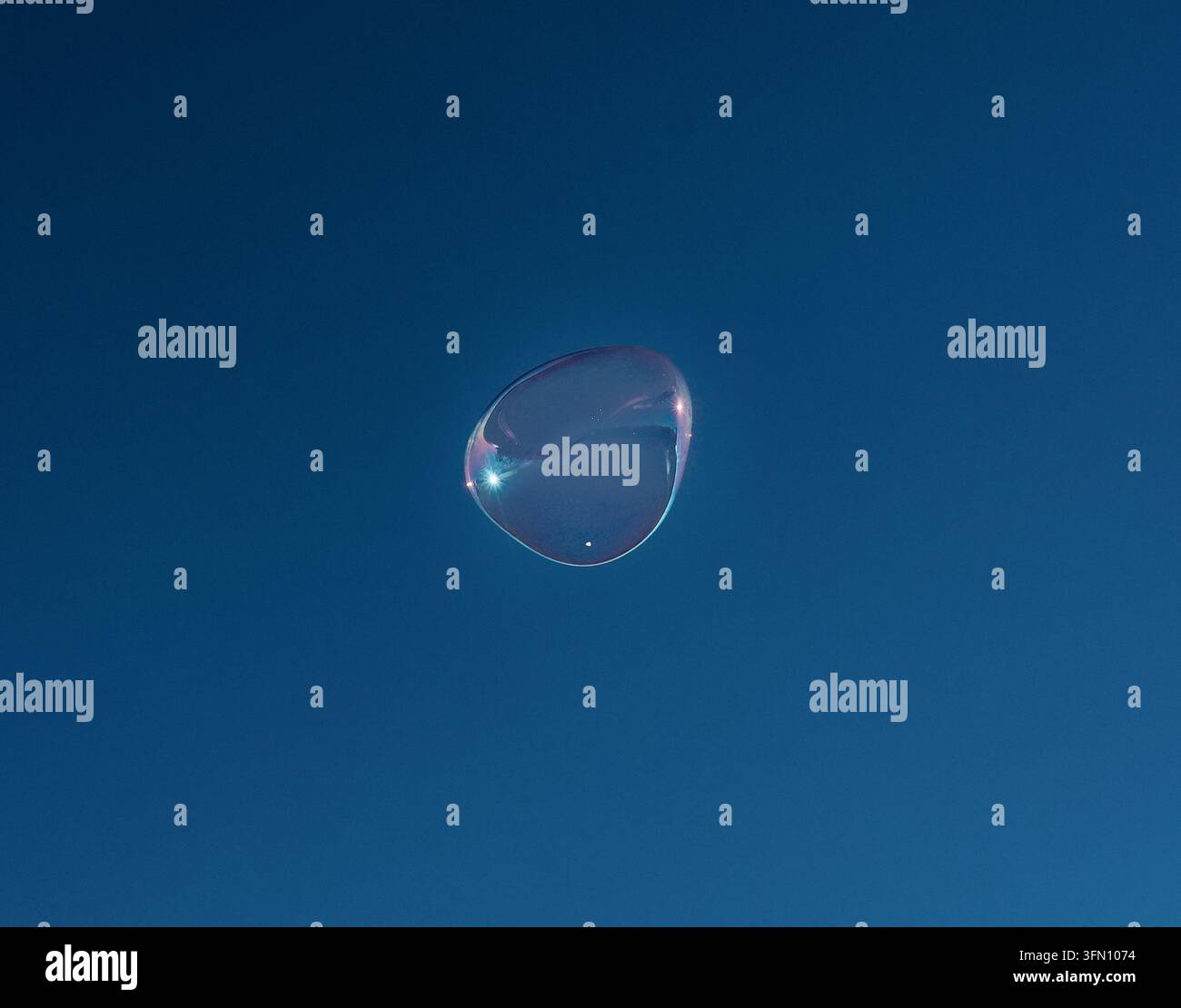 Iridescent Giant Soap Bubble Floating High Against a Deep Blue Sky Stock Photo