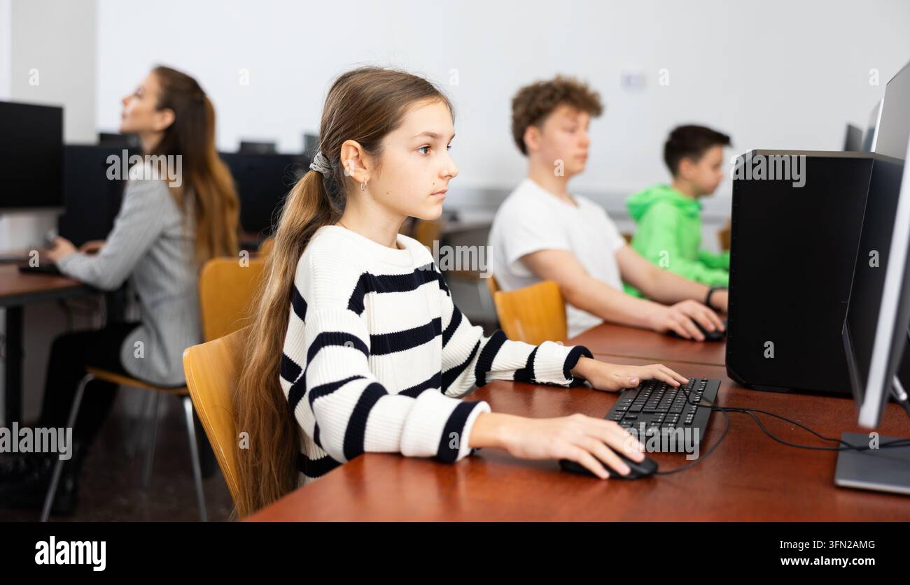 Pupils using computers at lesson, teacher teaching them in class room Stock Photo