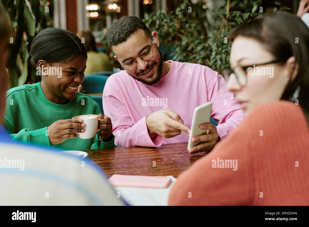 Diverse Friends Using Smartphone and Drinking Coffee in Cafe Stock Photo