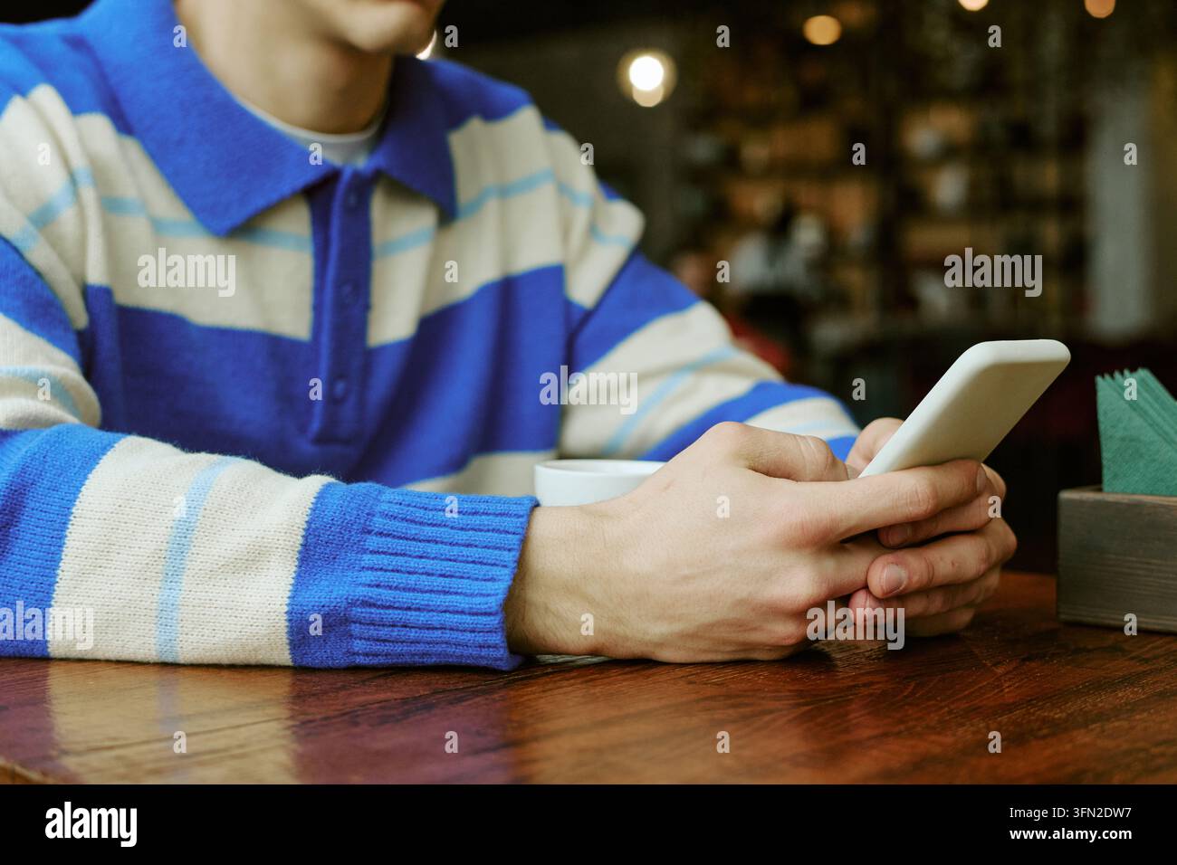 Man Using Smartphone for Messaging in Cafe Stock Photo