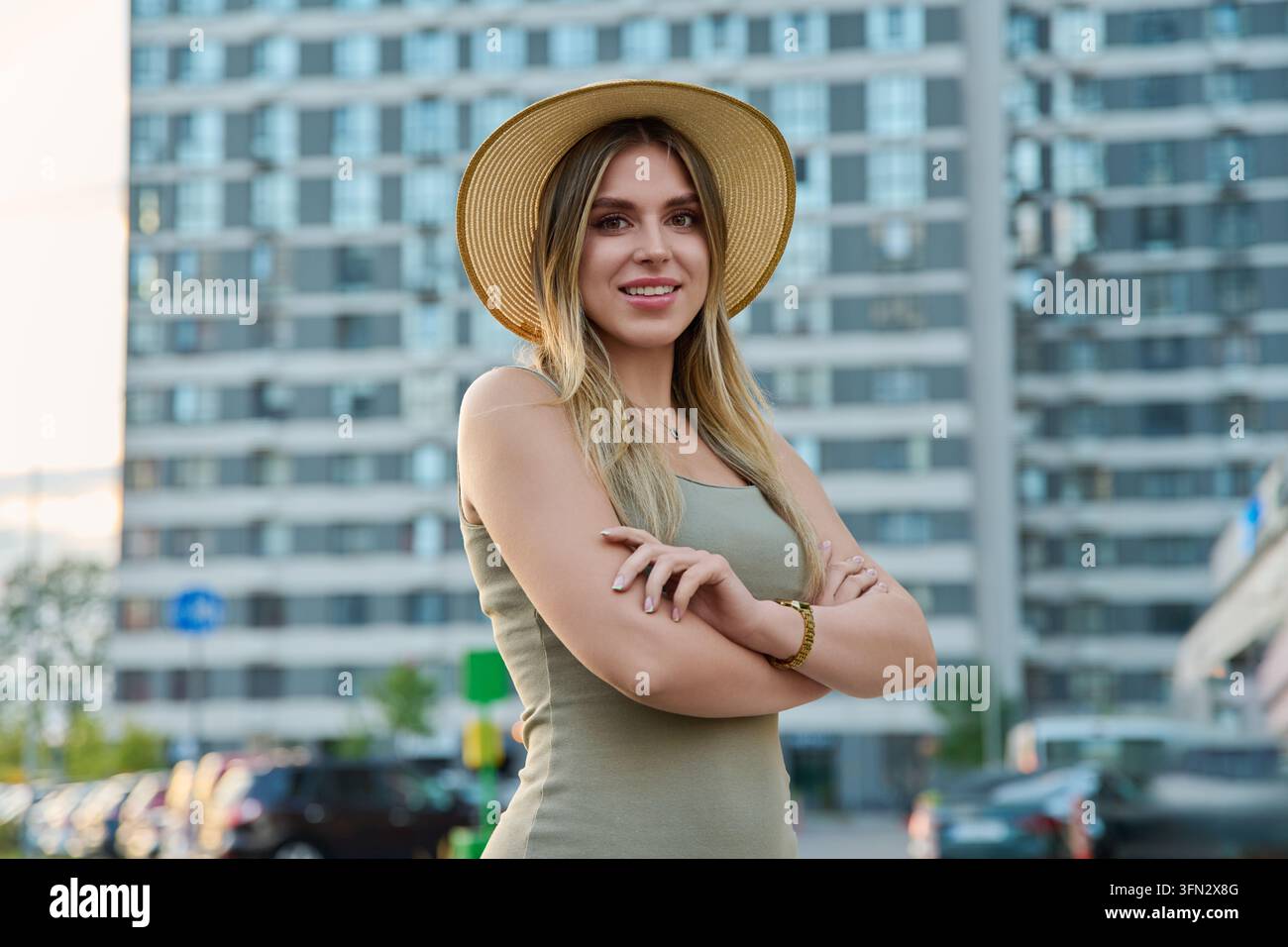 An attractive young woman in a straw hat and summer dress posing with ...