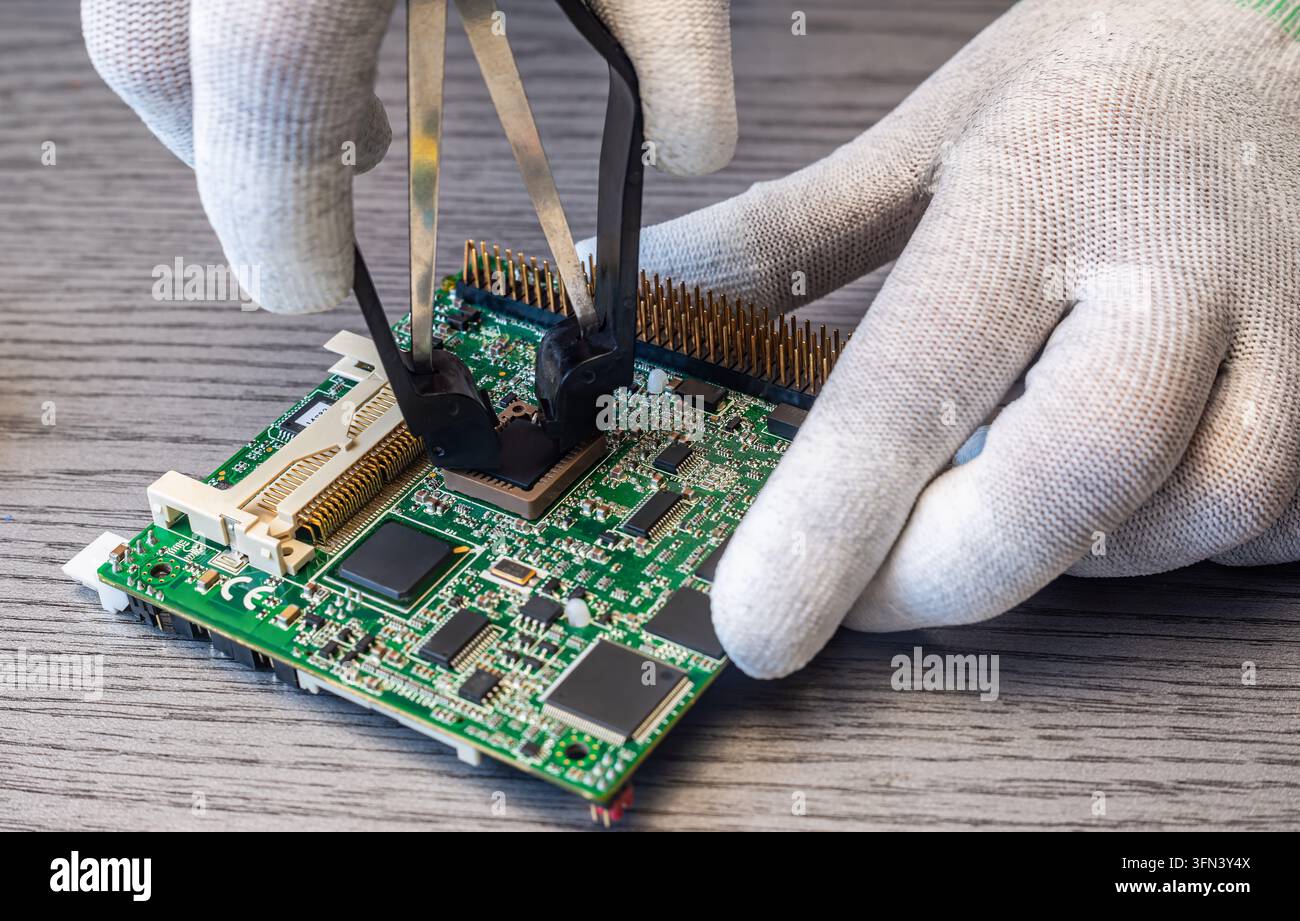 Technicians perform quality control by replacing components on a circuit board in a manufacturing environment during normal working hours. Stock Photo