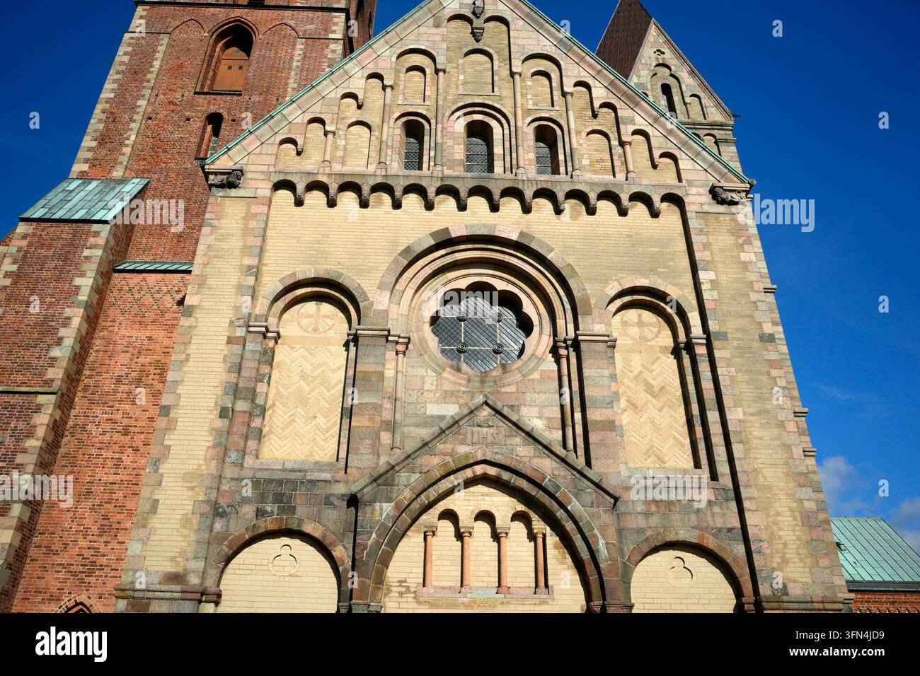 Close-up view of the ornate Romanesque west facade of Ribe Cathedral in Denmark, featuring arched windows, rose window, and decorative brickwork. Stock Photo