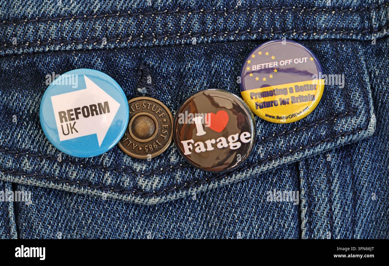 Reform UK and Nigel Farage supporter badges pinned to denim, with anti-EU campaign messaging. Stock Photo