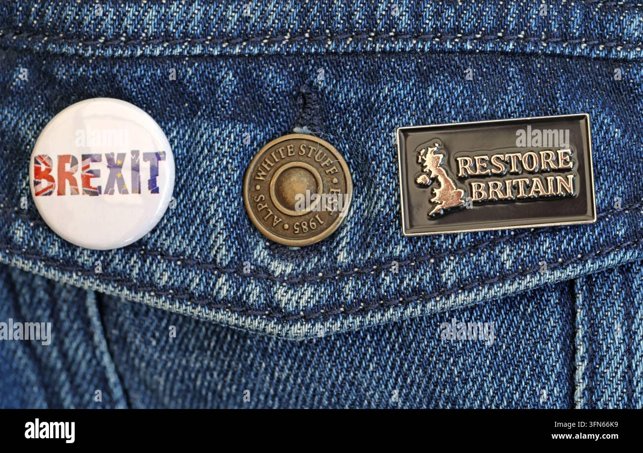 Restore Britain and Brexit badges pinned to denim, illustrating Rupert Lowe's party and British right-wing politics. Stock Photo