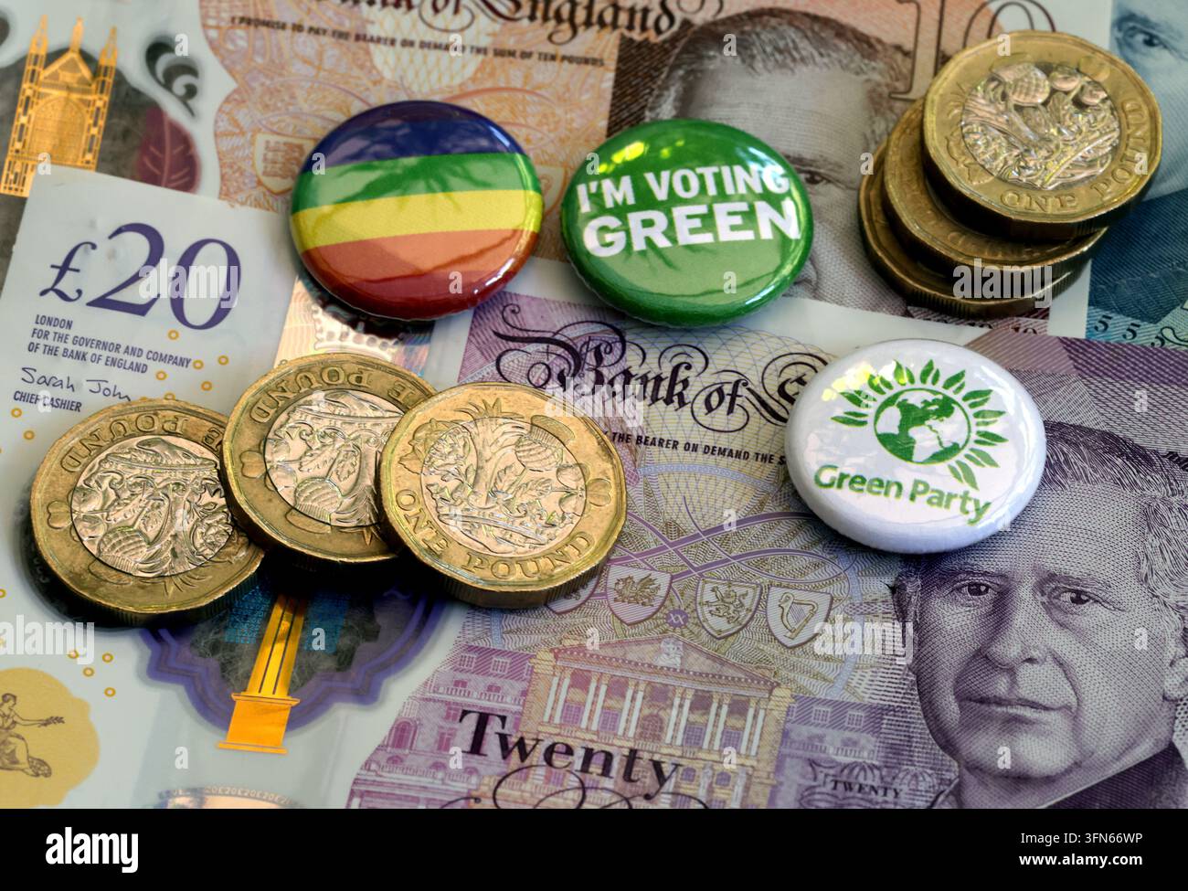 Green Party political badges with sterling banknotes and coins, illustrating party funding in UK politics. Stock Photo