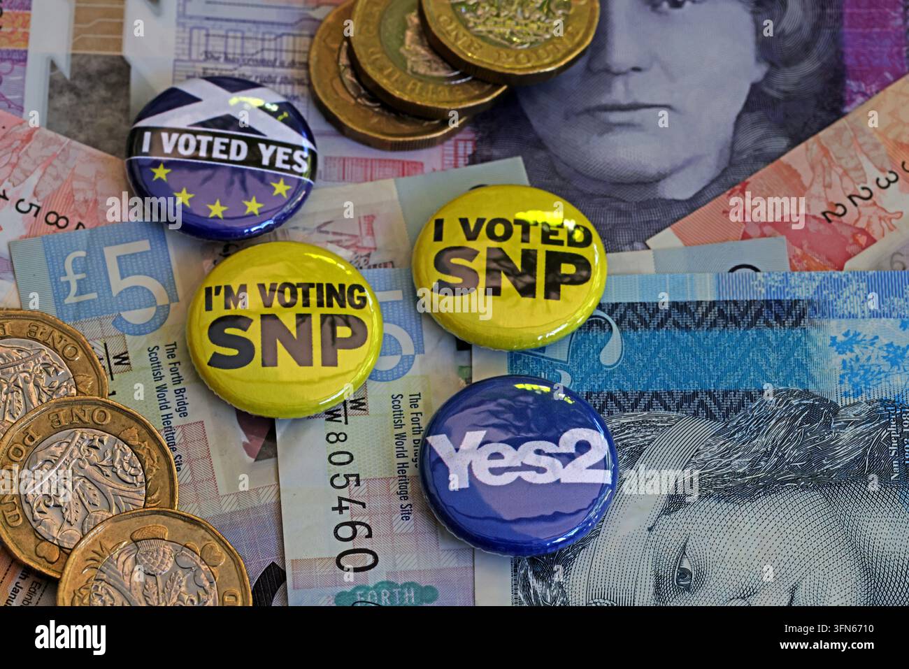 SNP voter badges, Scottish banknotes and coins illustrating Scottish National Party political funding and campaigning. Stock Photo