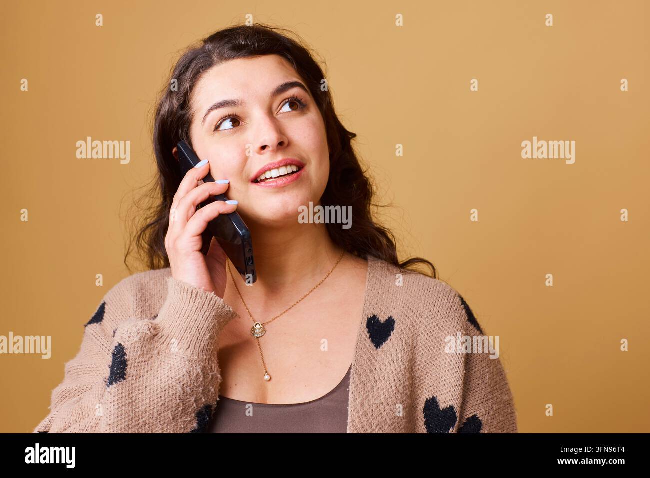 Young Woman Talking On Phone With Happy Expression Wearing Heart Cardigan Casual Portrait Stock Photo