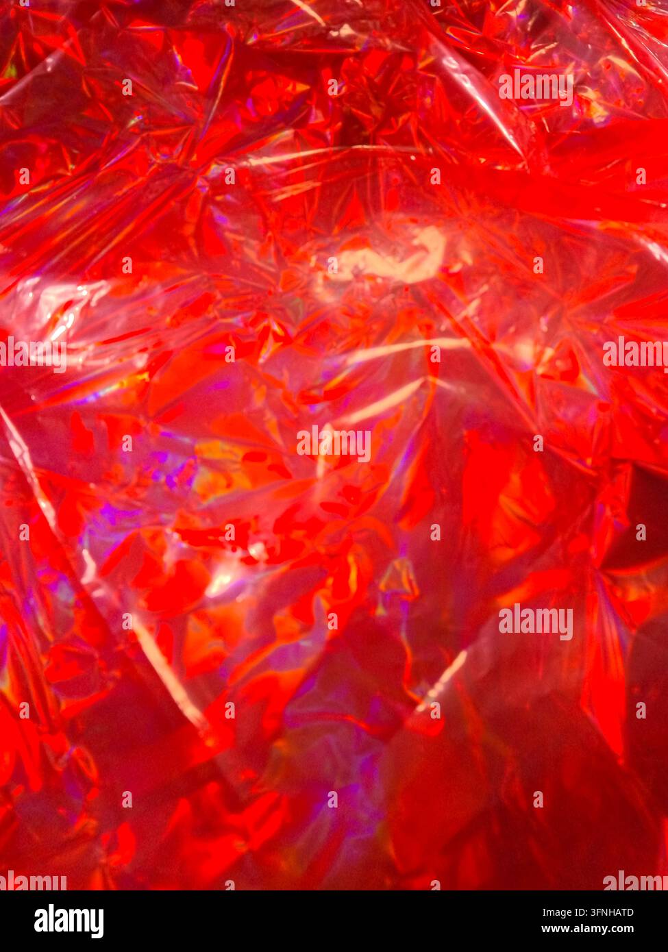 Vibrant red wrinkled plastic sheeting creates abstract textured background. Sharp highlights and diffused shadows add depth. Ideal for design elements Stock Photo