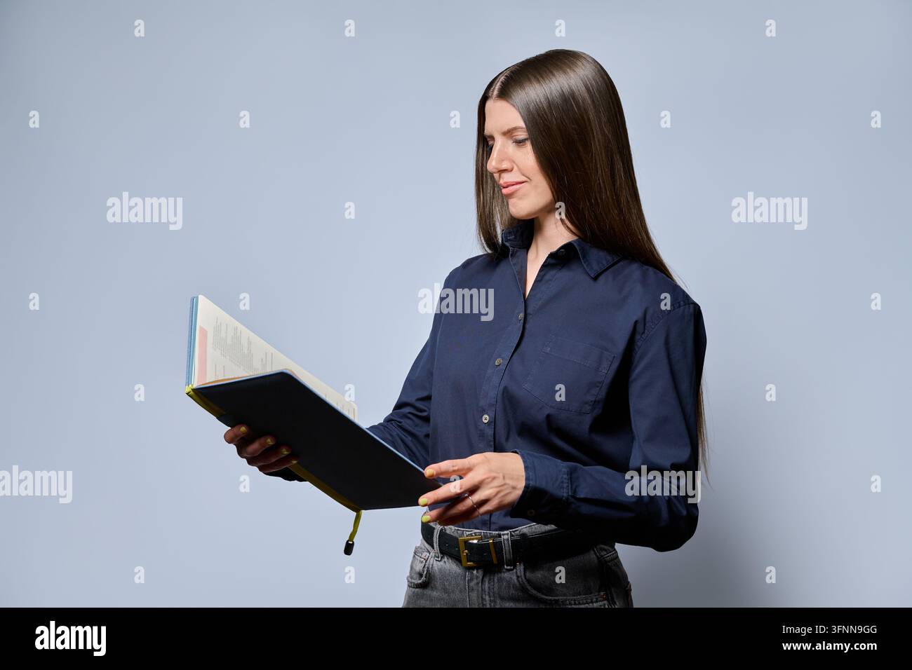 Young focused woman reading notebook in studio portrait Stock Photo