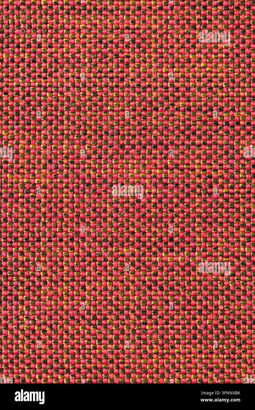 Detailed macro shot of a tight patterned textile featuring an alternating grid weave of bright red and olive green yarn threads with crisp high-contra Stock Photo