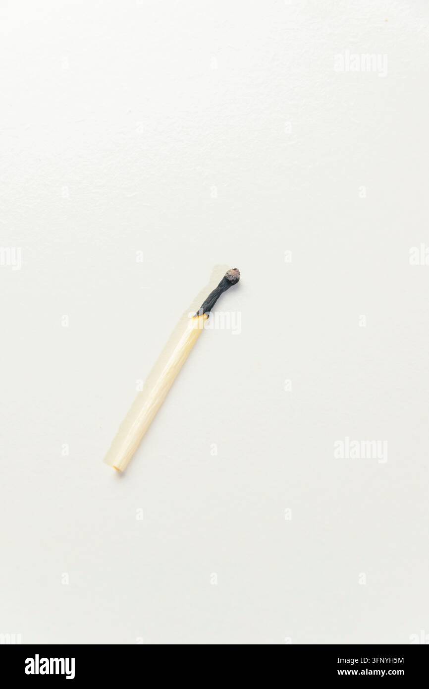 Close-up photo of an extinguished burnt wooden matchstick resting on a ...