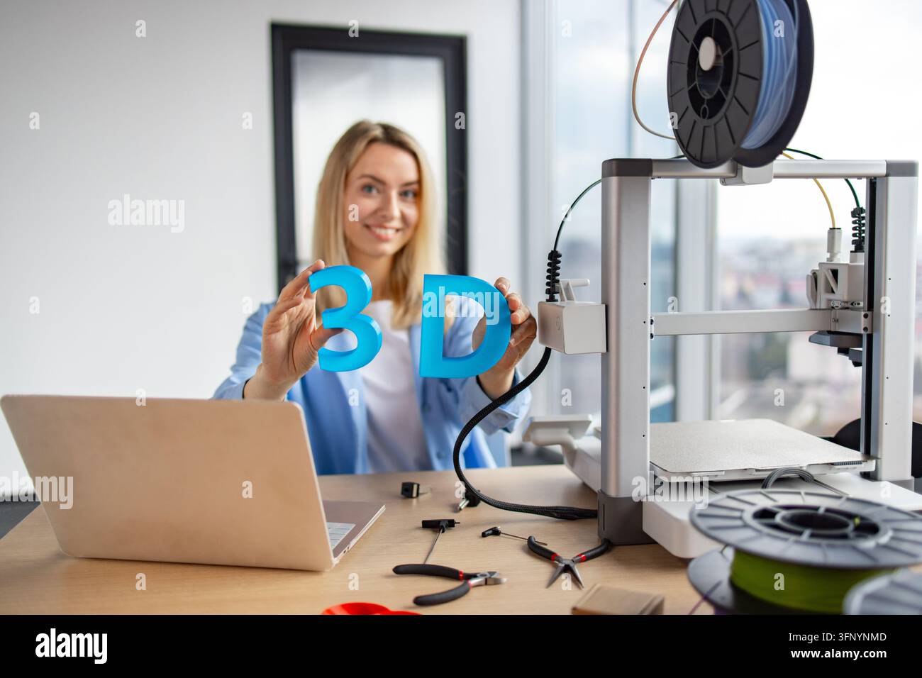 Alphanet Notebook A smiling woman holds the letters '3D' next to a 3D printer and laptop ...
