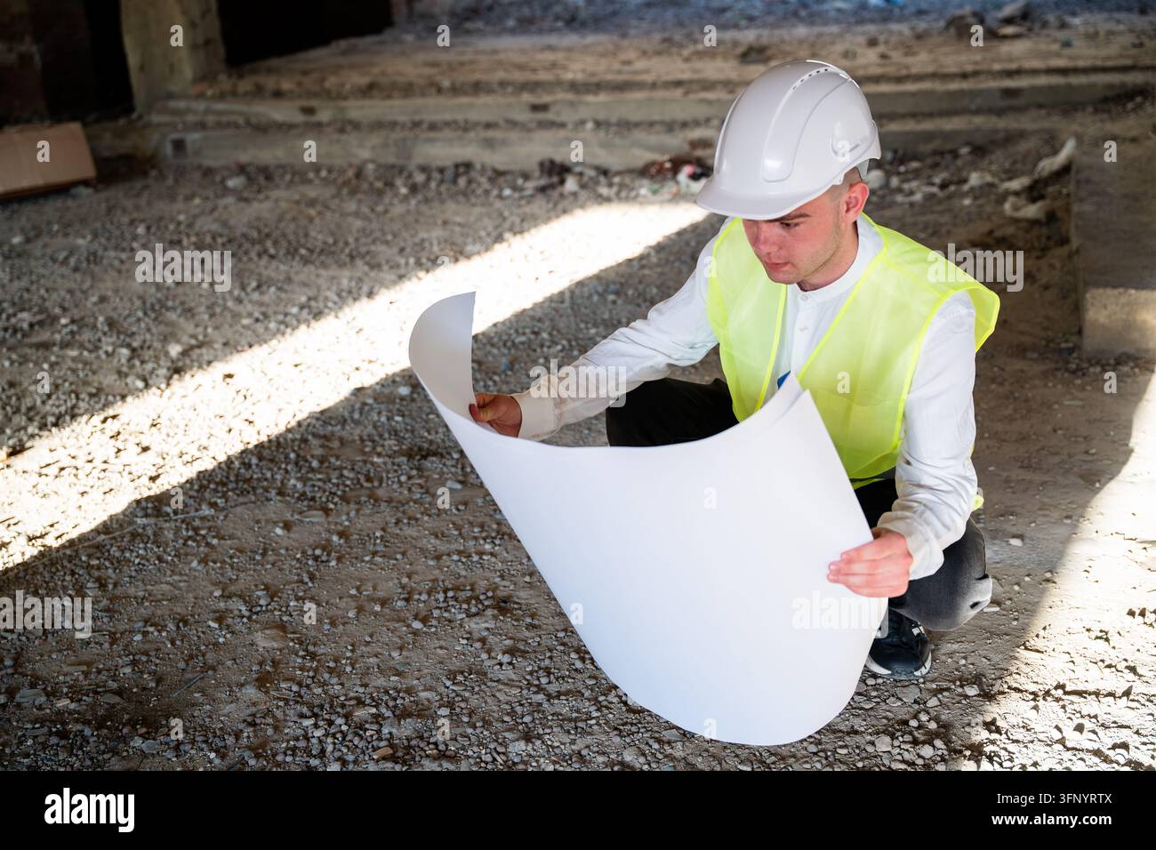 Construction professional reviewing large architectural plans inside an ...