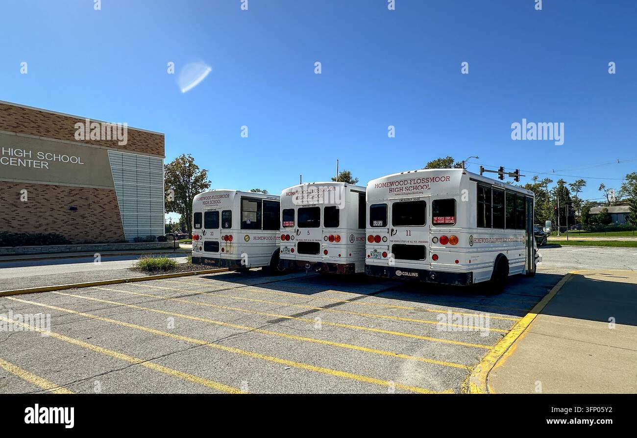 Three school buses parked in a designated lot at Homewood-Flossmoor High School Center on a sunny day. Flossmoor, IL USA - October 4, 2026 - Smartphone Captured Stock Image