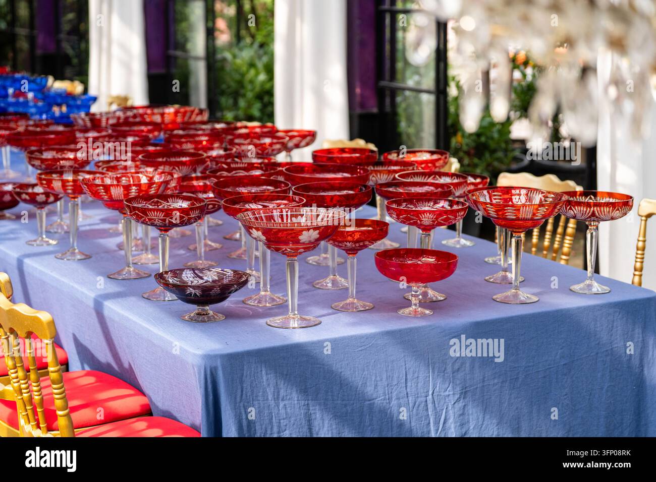 Rows of vintage red crystal glasses prepared on banquet table for elegant festive reception Stock Photo