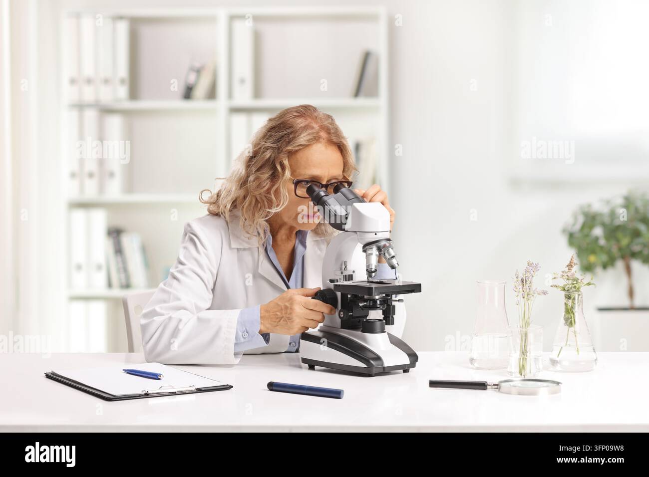 Female scientist looking through a microscope in a laboratory Stock Photo