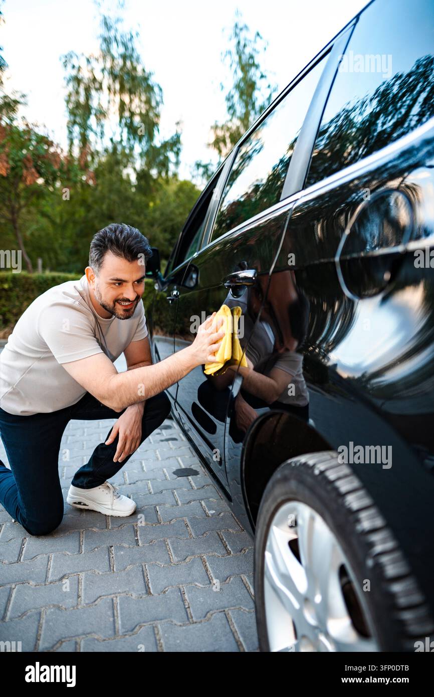 Man polishing black car exterior during auto detailing Stock Photo
