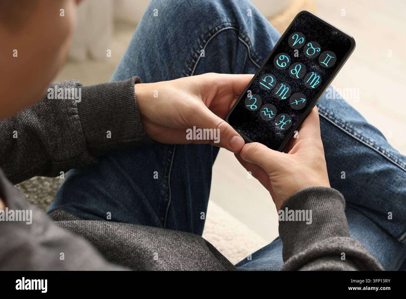 Man using astrology app on his smartphone indoors, closeup Stock Photo