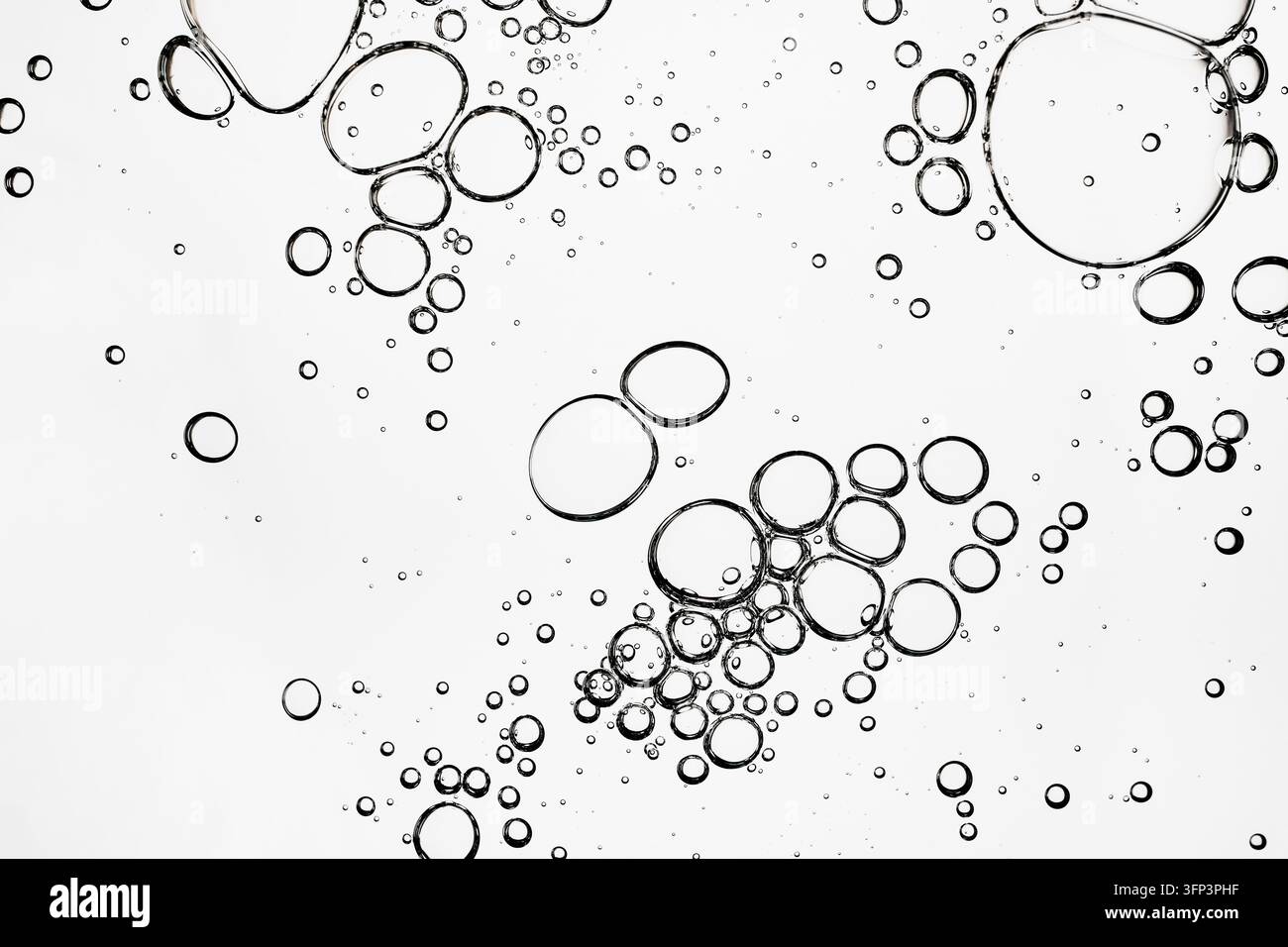 Transparent liquid bubbles creating an abstract pattern on white background Stock Photo