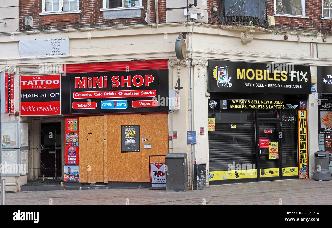 A boarded Mini Shop entrance beside a mobile phone repair shop on Horsemarket Street, Warrington. Stock Photo