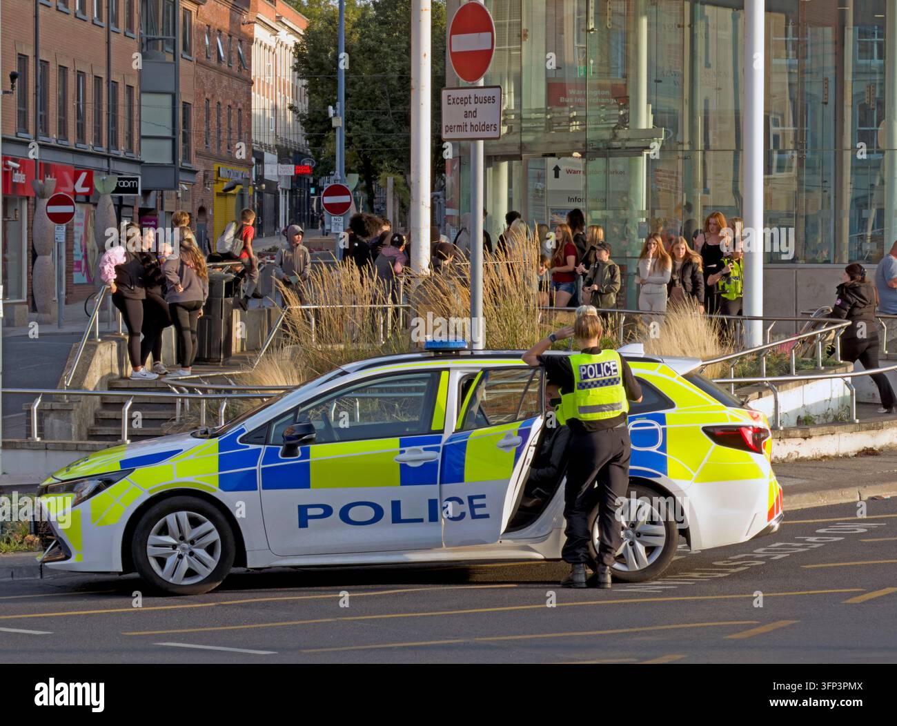 Cheshire Police officers and a marked patrol car in a Warrington public area with pedestrians nearby. Stock Photo