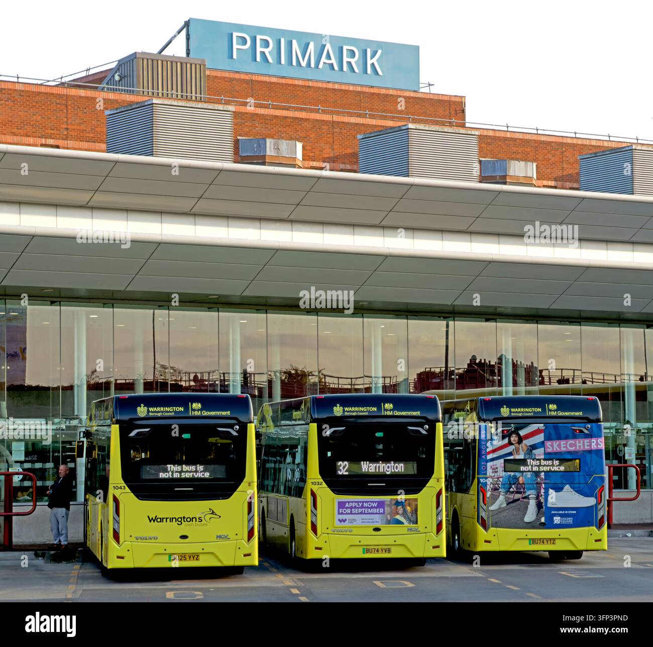 Warrington's Own Buses at the town centre interchange, with Golden Square and Primark signage visible beyond the stands. Stock Photo