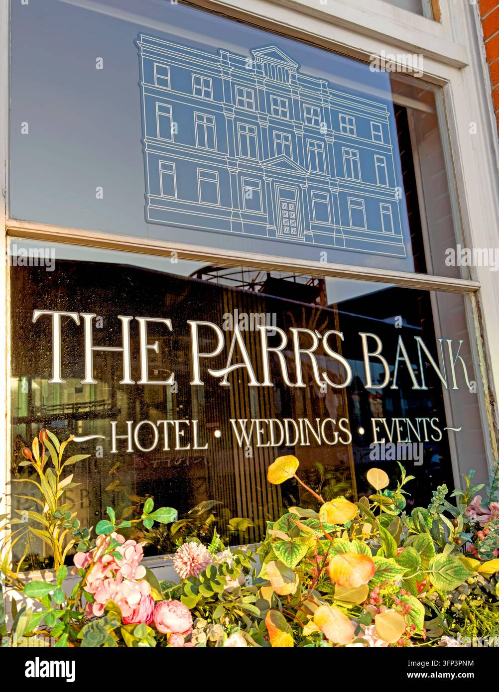 Window lettering for THE PARR'S BANK advertises HOTEL, WEDDINGS and EVENTS, with flowers arranged outside the former bank building. Stock Photo