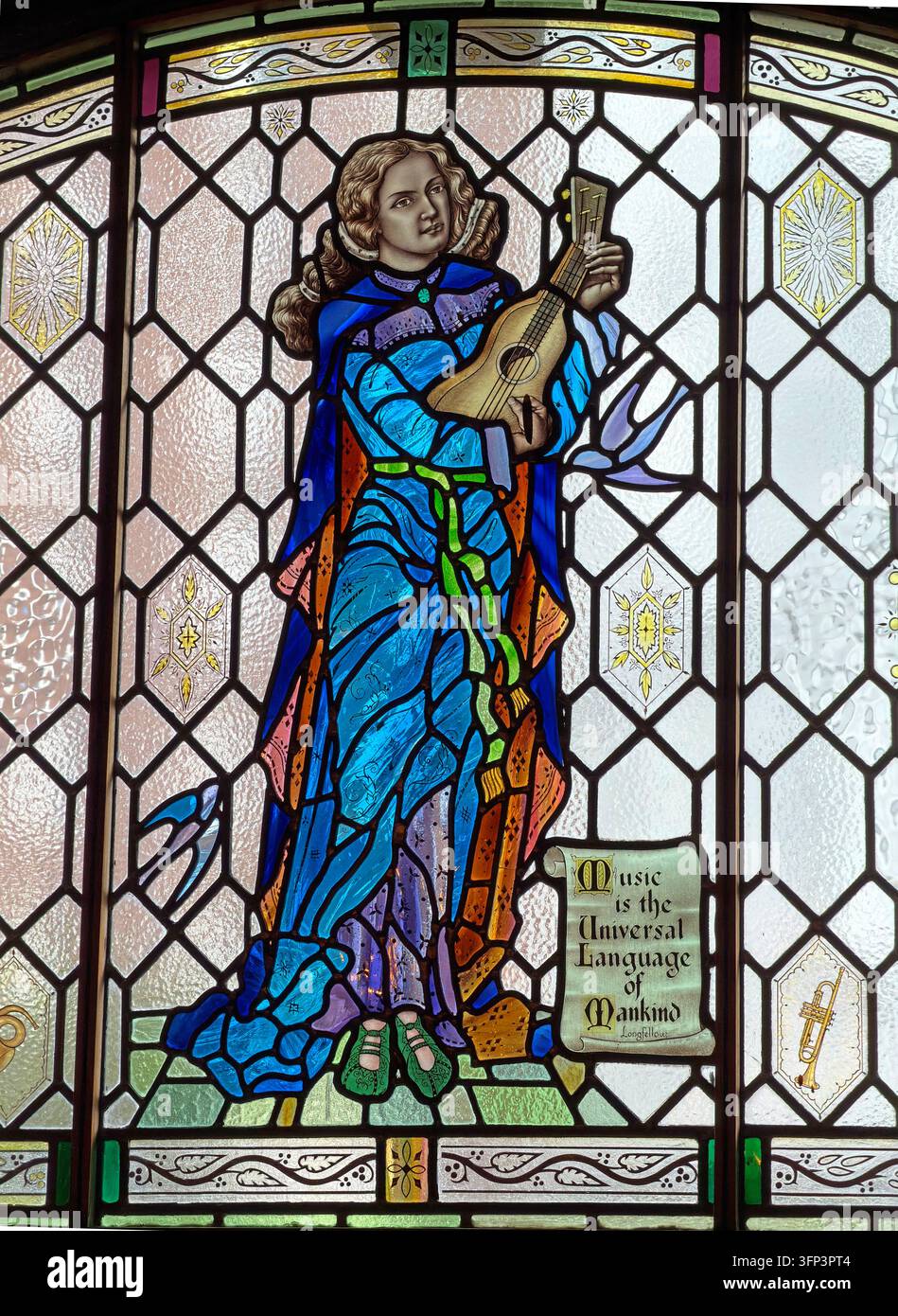 A richly coloured stained-glass window depicts a figure playing a stringed instrument and carries words about music as a universal language. Stock Photo