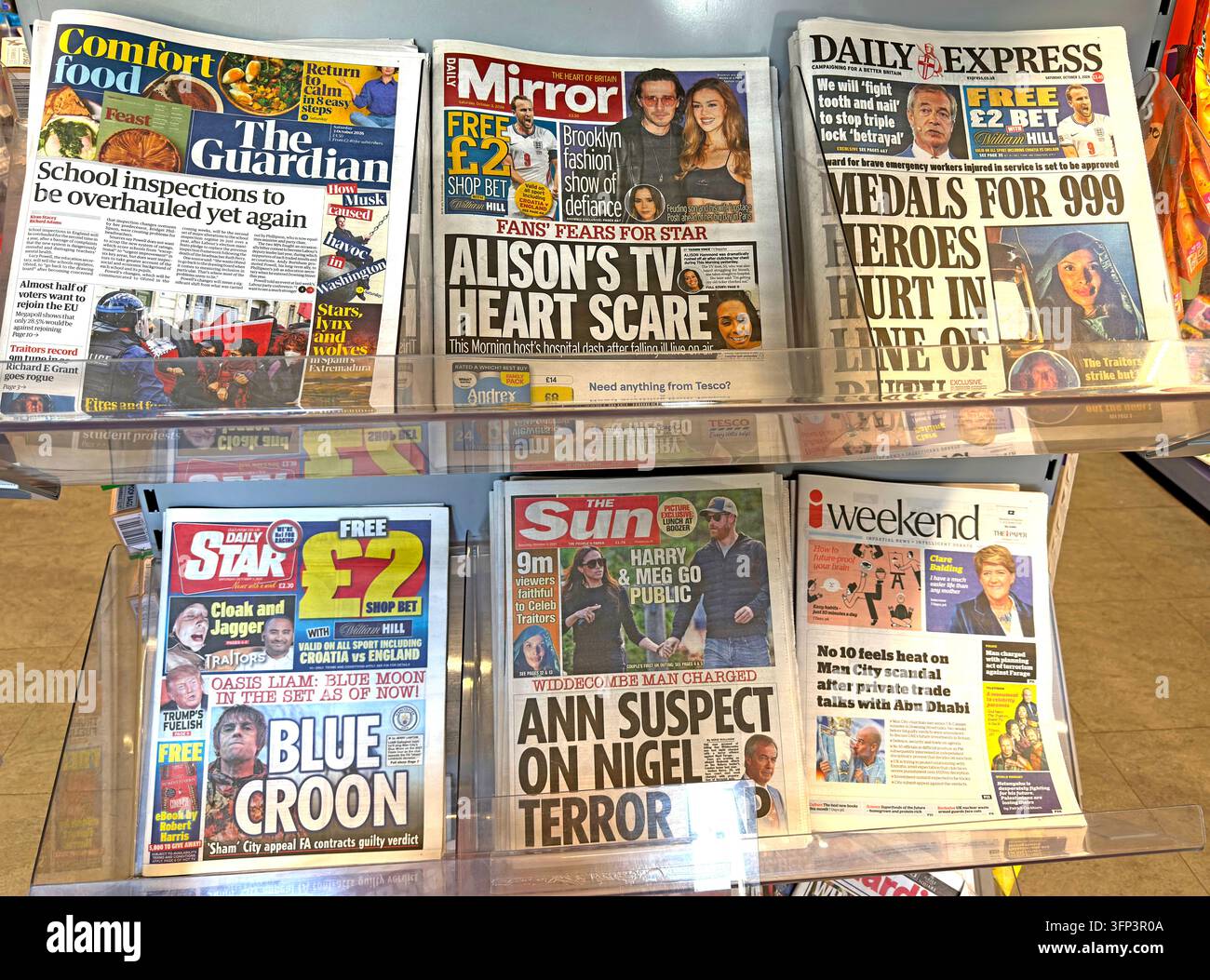 An array of British newspapers is spread across a newsstand, including tabloid and mid-market mastheads with large headlines. Stock Photo