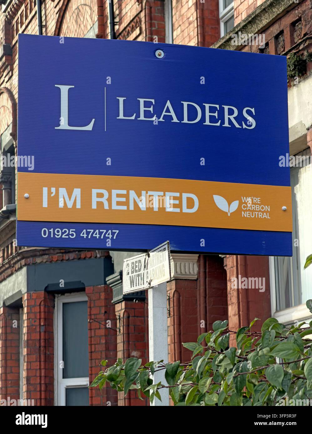 A large blue Leaders letting-agent board has an orange panel reading I'M RENTED outside a brick residential property. Stock Photo