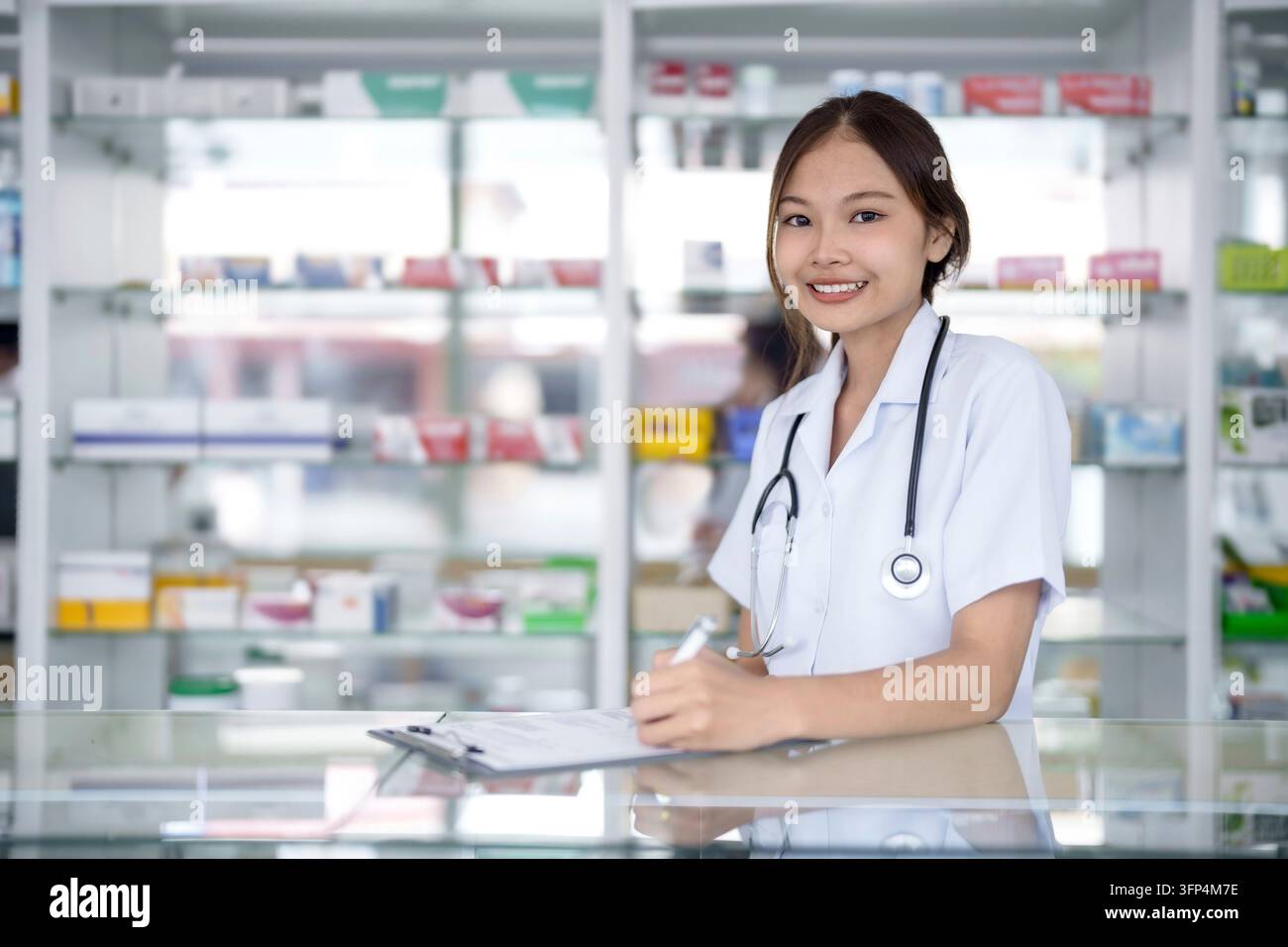 Portrait of asian pharmacist working in pharmacy with medication at pharmacy counter Stock Photo