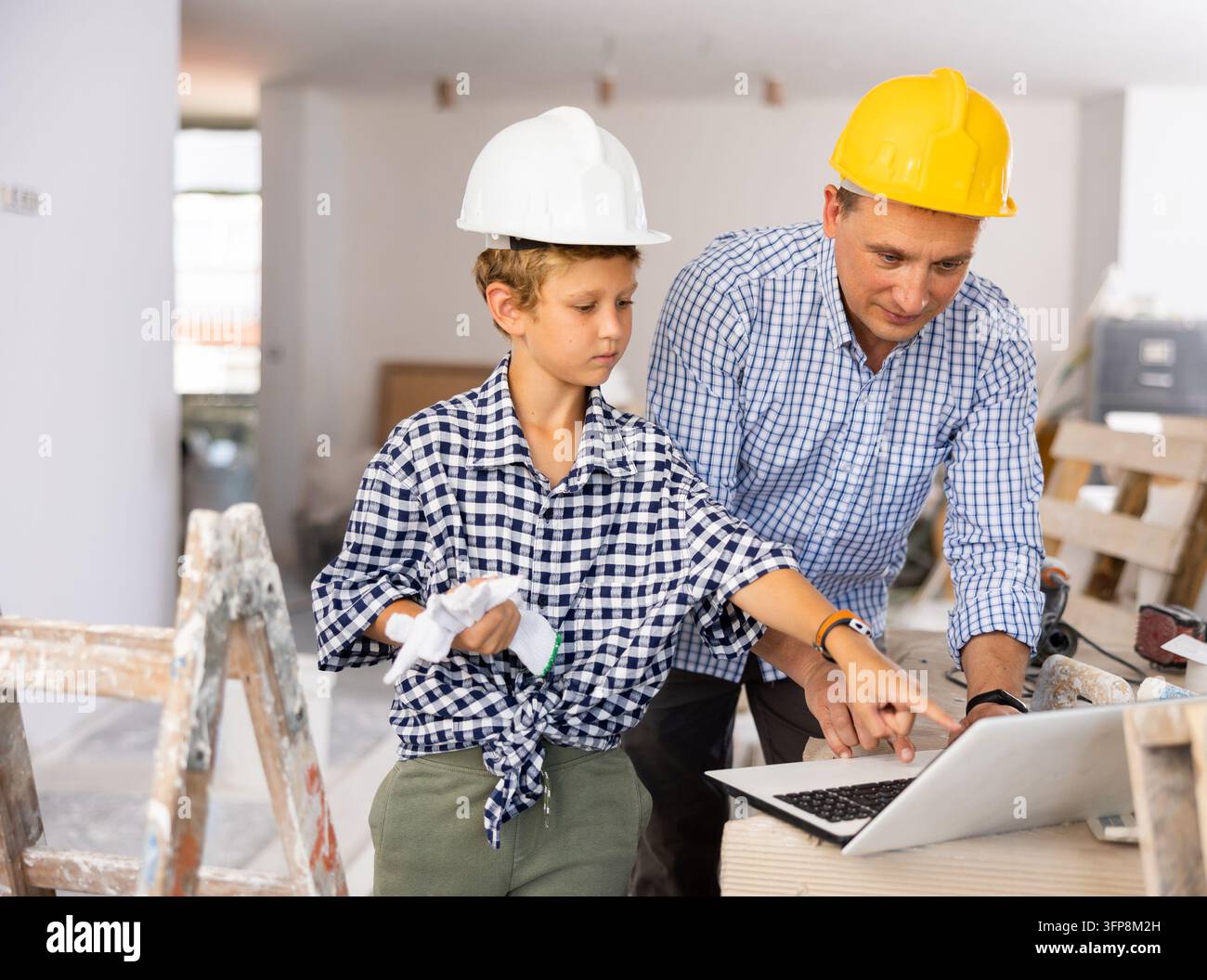 Portrait of man architect and boy using laptop while discussing working process in house being renovated Stock Photo