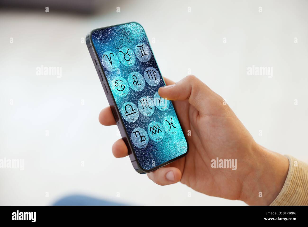 Man using astrology app on his smartphone indoors, closeup Stock Photo