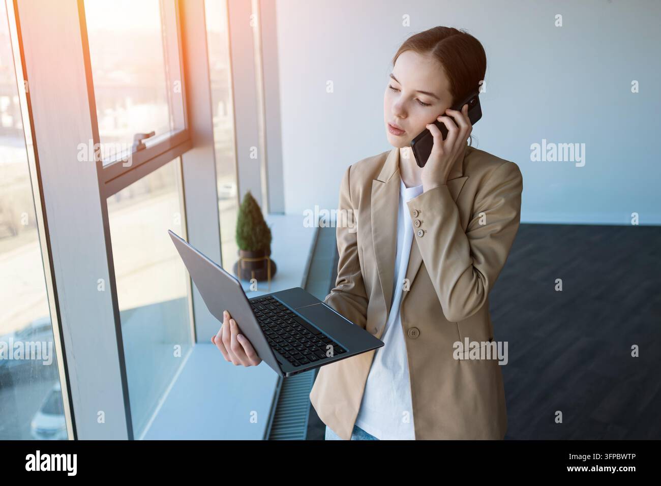 Businesswoman multitasking working remotely talking on smartphone Stock Photo