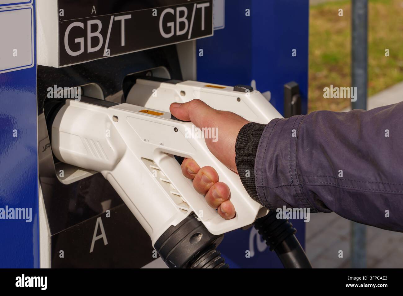 Man hand holding charging plug at public station. Interaction with ...