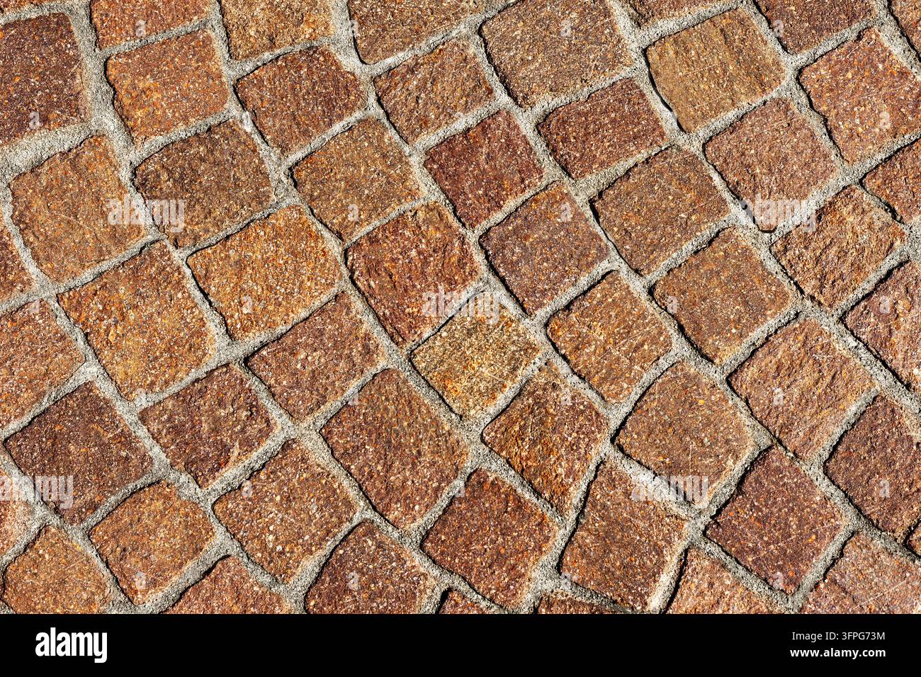 Warm reddish brown porphyry cobblestone pavement texture arranged in arched fan pattern for classic European street design with copy space Stock Photo