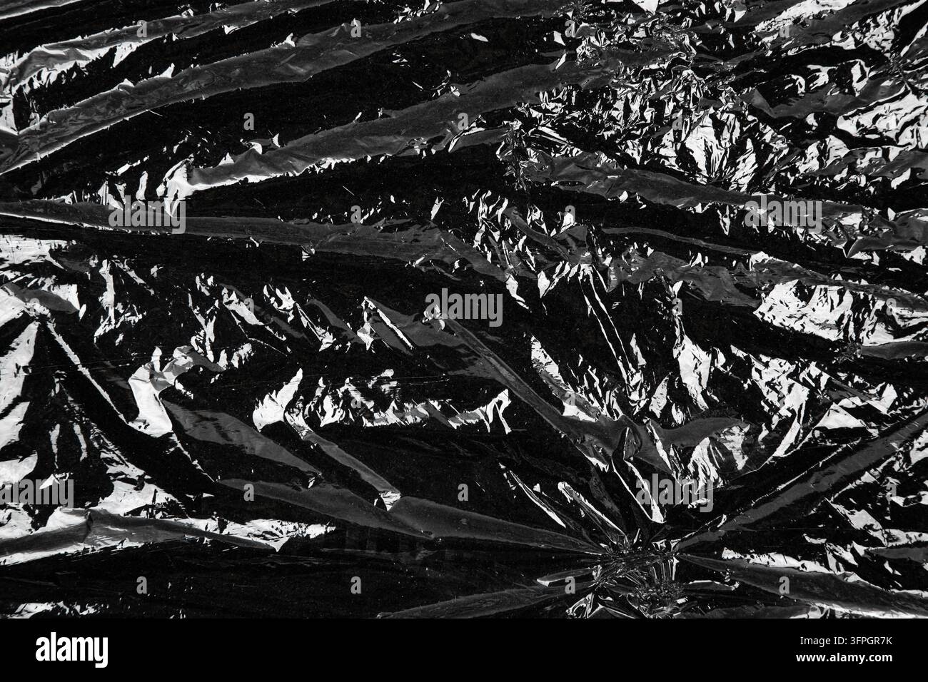 Abstract crumpled black plastic film texture close up. Stock Photo