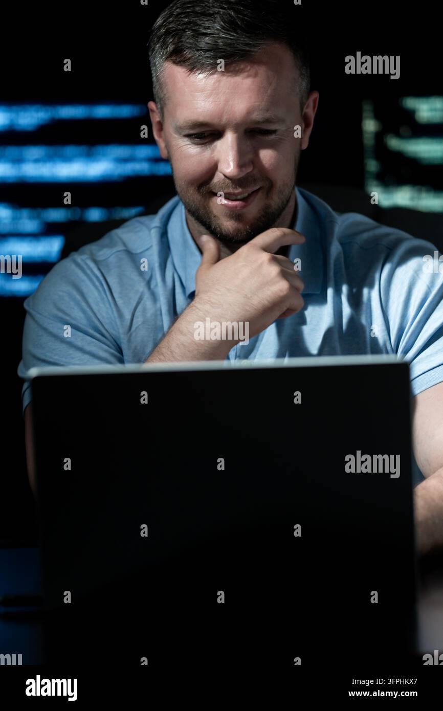 Programmer works in technology workplace. Programmer writes coding for software system. Programmer monitors network and cybersecurity threats Stock Photo