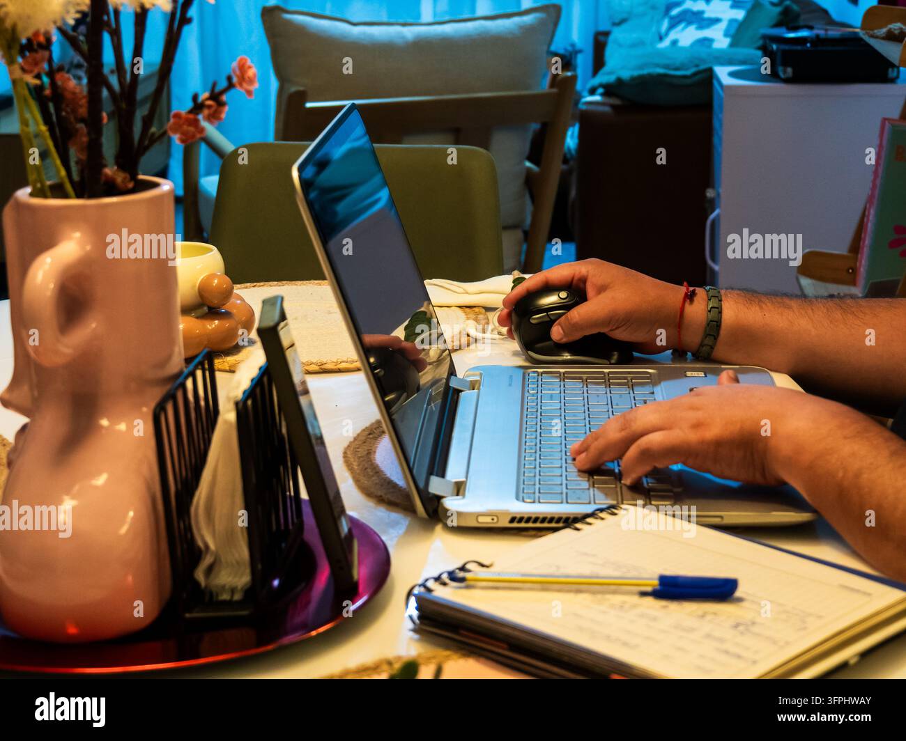Comp Tabel Close-up view of a person working remotely at a dining table, using a ...