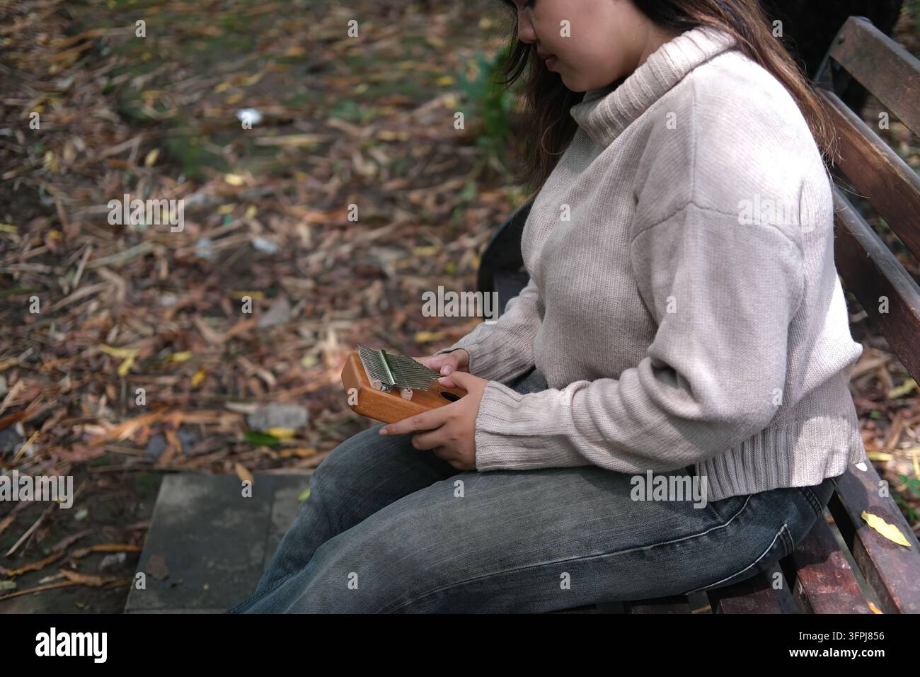 Asian Kitchen Portrait of Asian woman in sweater playing kalimba music box at city ...