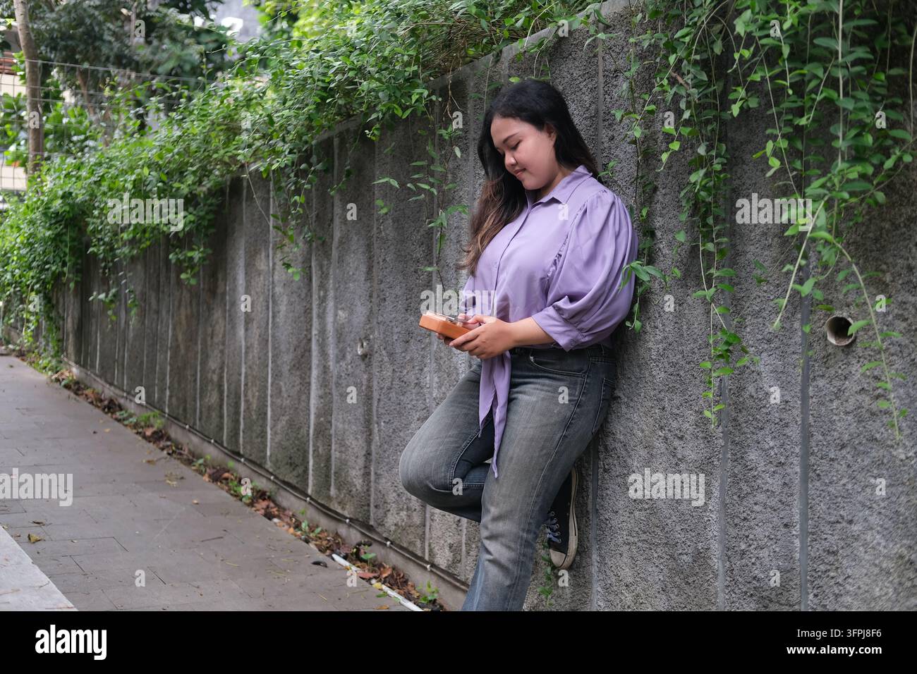 Asian Kitchen young Asian woman plays a kalimba while relaxing in a green city park ...