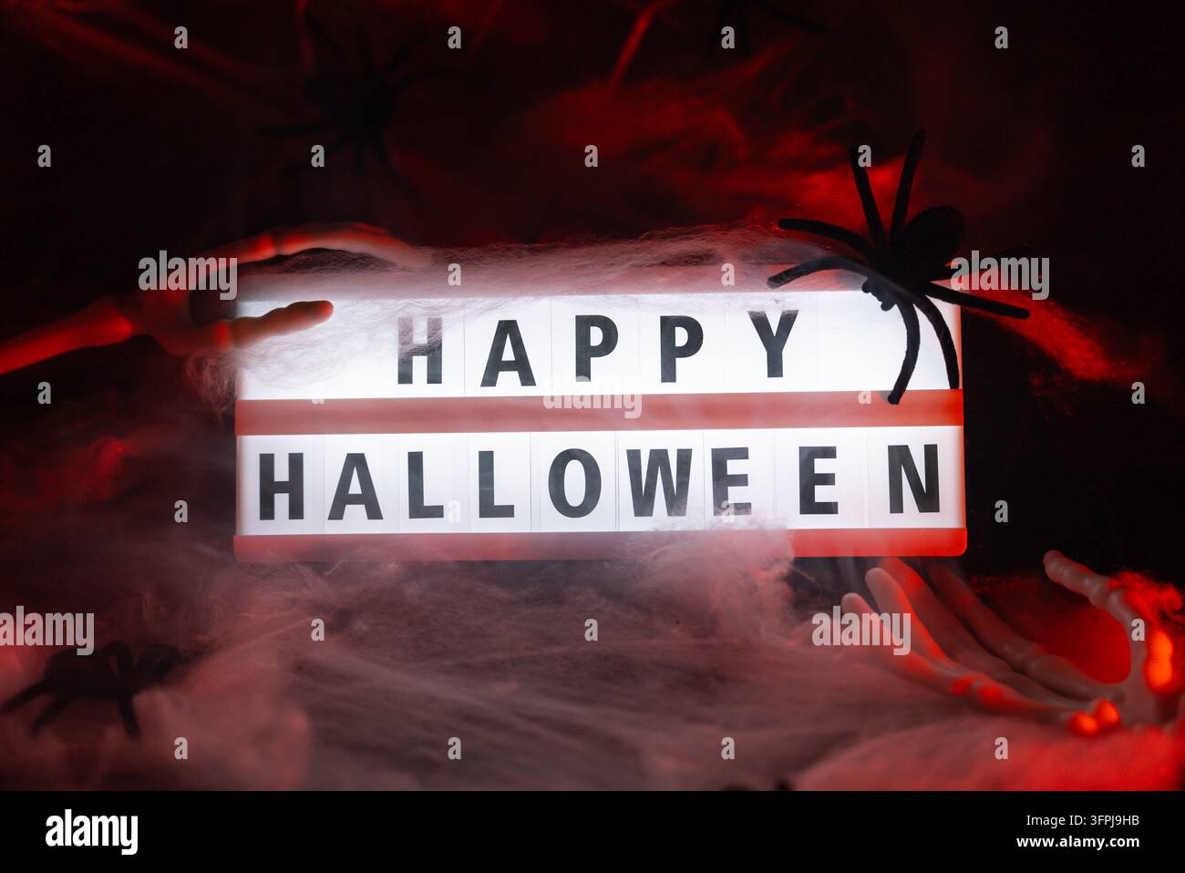 Dark still life featuring illuminated lightbox with HAPPY HALLOWEEN ...