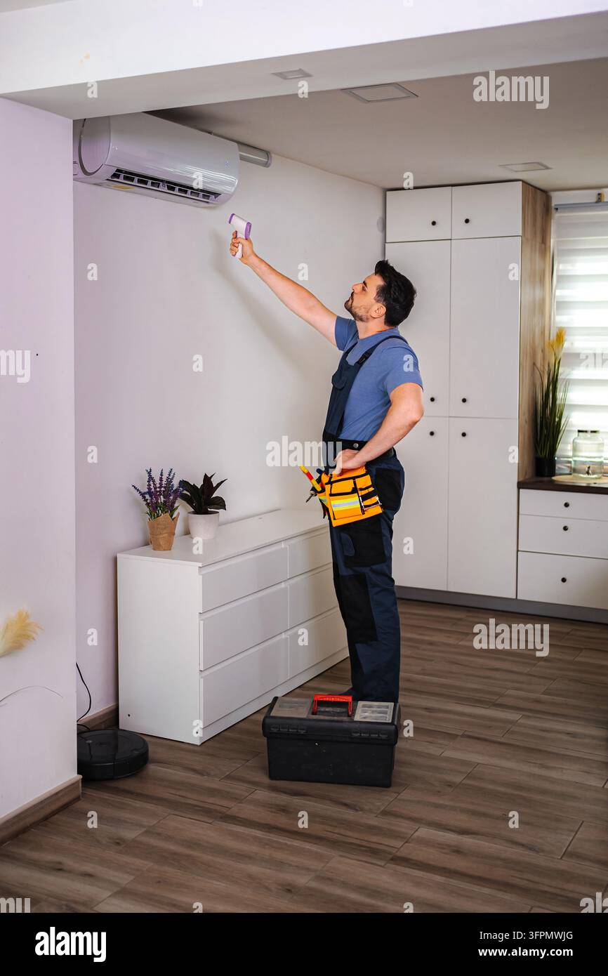 Technician checking air conditioner temperature with infrared thermometer Stock Photo