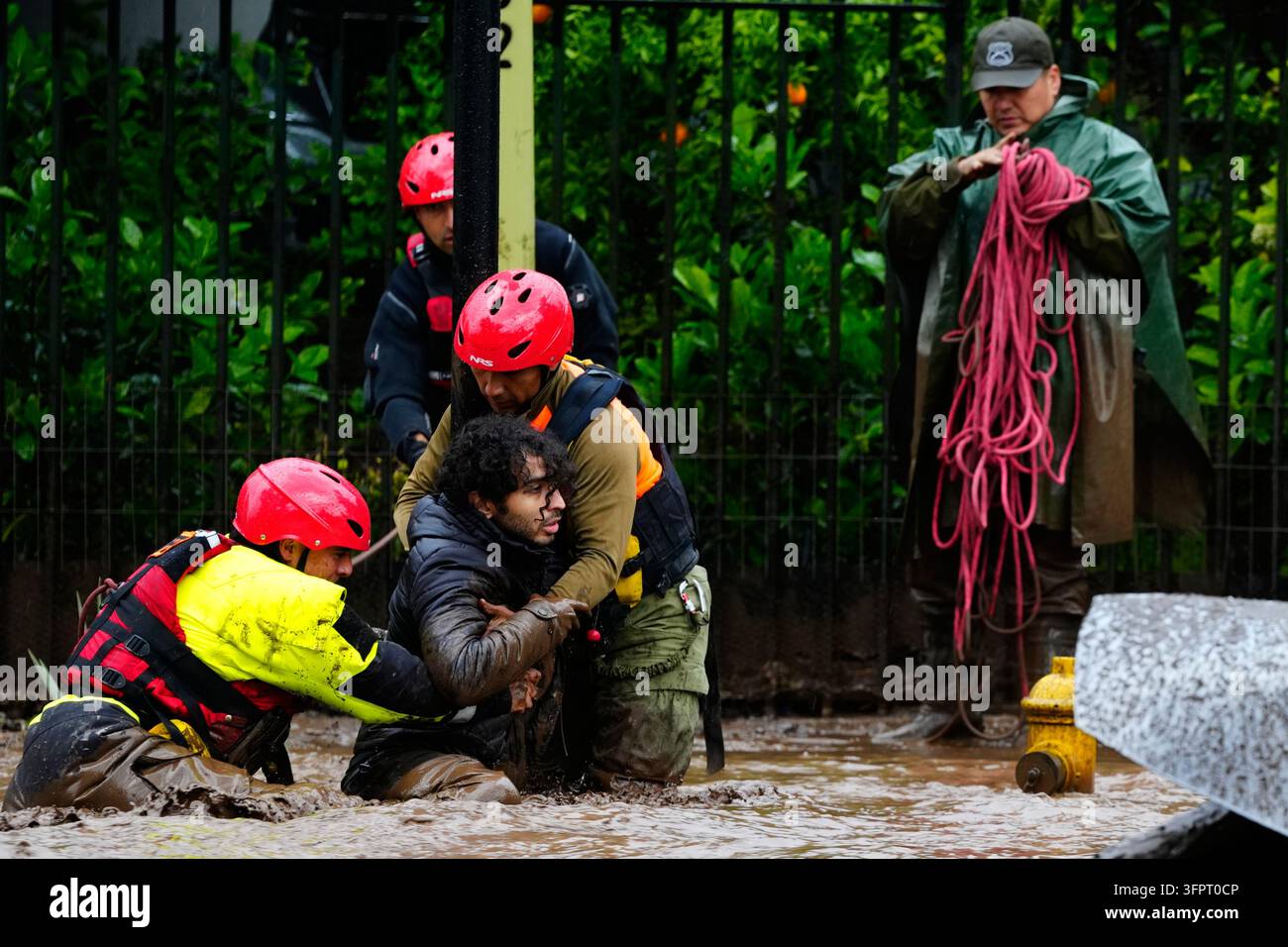 A man is pulled to safety by rescue workers after heavy rains caused ...