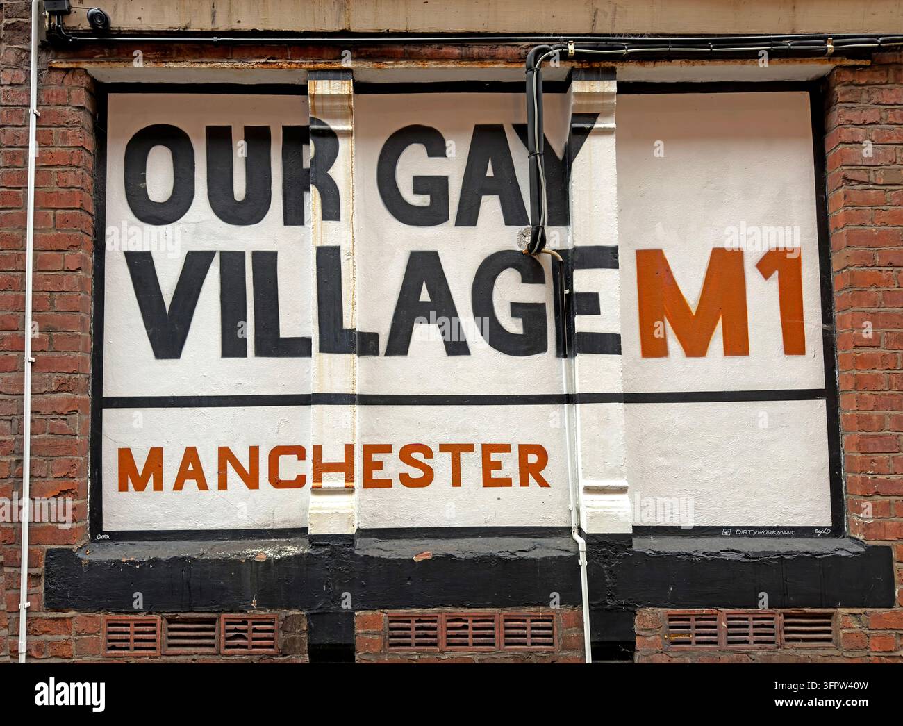 An Our Gay Village M1 wall sign appears on a brick building on Richmond Street in Manchester’s Gay Village. Stock Photo