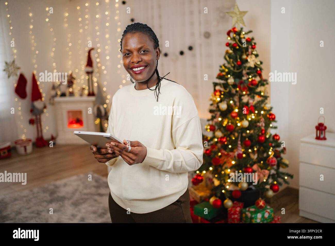 Woman holding tablet celebrating Christmas at home Stock Photo