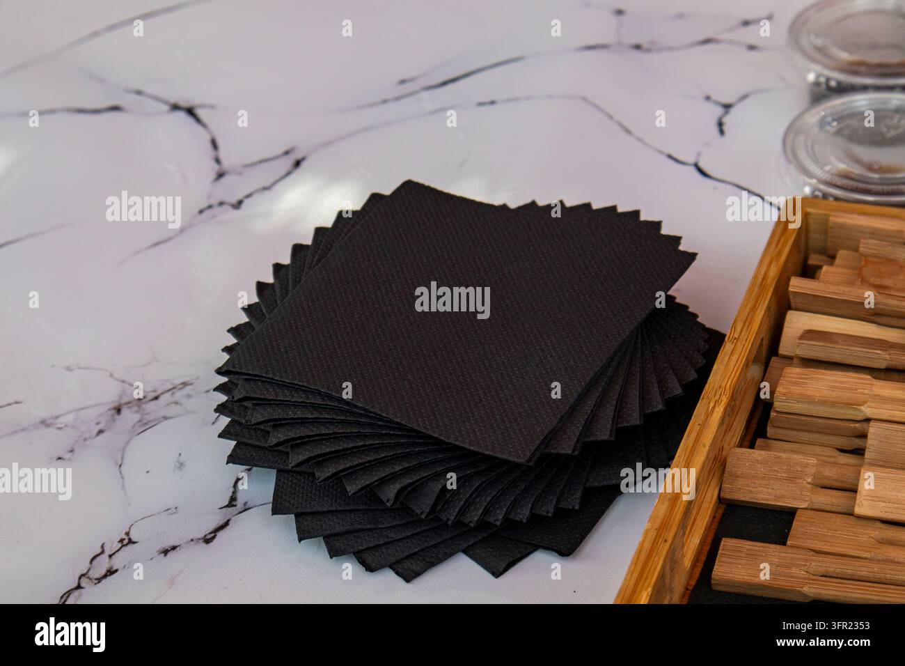 Fanned stack of black paper napkins on white marble background Stock Photo